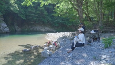 休む家族と水辺で遊ぶ2匹の犬