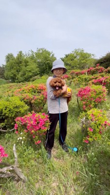 花をバックに犬を抱っこする女性