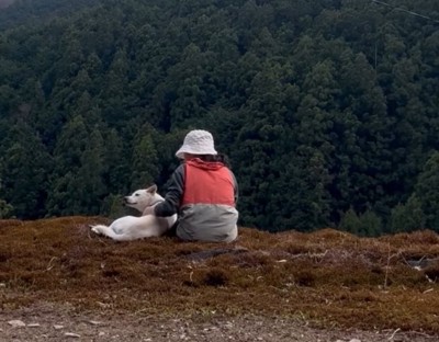 山々を眺める女性と犬