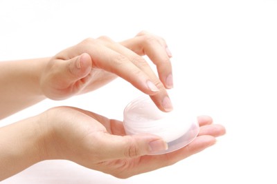 保湿クリームを容器から取る人の手