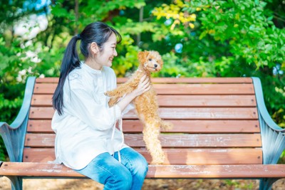 公園で犬に話しかける女性と他所を向く犬