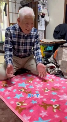 手を広げて犬を呼ぶ男性