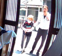 男性に支えられながら家に向かって歩く老年女性