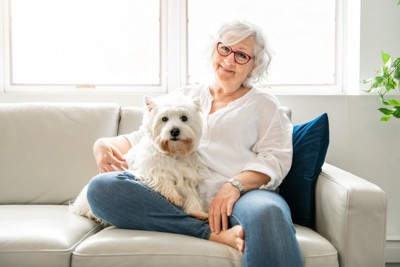 ソファーで微笑む高齢の女性と犬