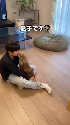 座っている男の子の口を舐める犬