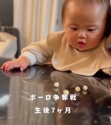 机に散らばったボーロを見つめる赤ちゃん