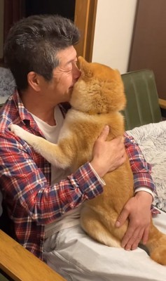 飼い主と向かい合ってキスされている柴犬