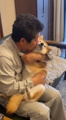 犬の頬に顔を寄せる男性