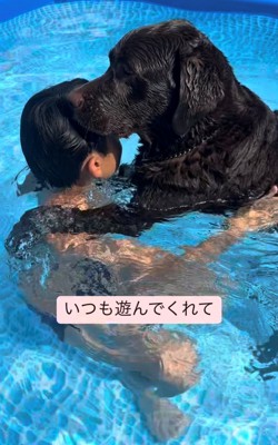 プールで子どもと犬が抱き合っている