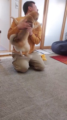 犬に飛びつかれて、笑顔で顔を背ける男性