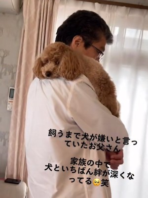 飼い主に抱かれている小型犬