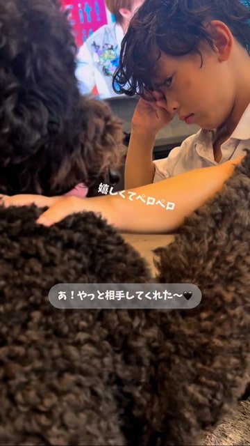 目をこすりながら犬をなでる男の子