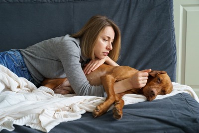 体調不良の犬と心配する女性