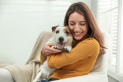 女性に抱きしめられる犬