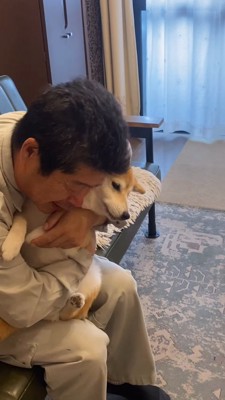 抱きしめている犬を床に降ろそうとする男性