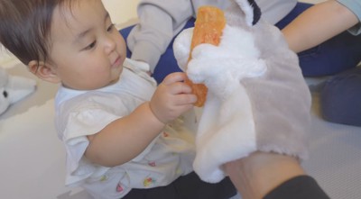 パペットにおやつを渡す赤ちゃん