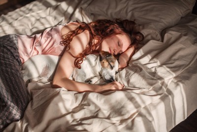 ベッドで眠る女性と犬
