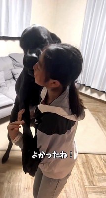 女の子の腕に前足を置く黒い犬