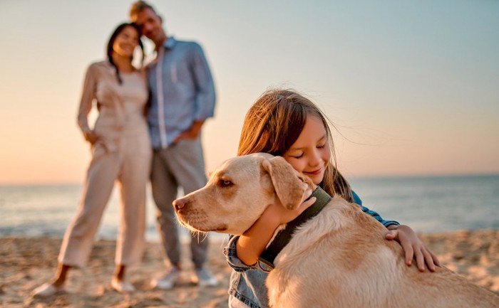 犬を抱きしめる女の子と見守る両親