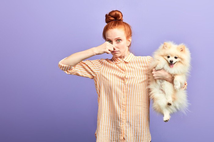 犬を抱き抱えて鼻を抑える女性