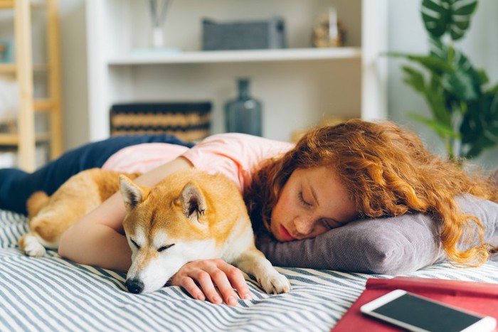 寄り添って一緒に眠る女性と犬