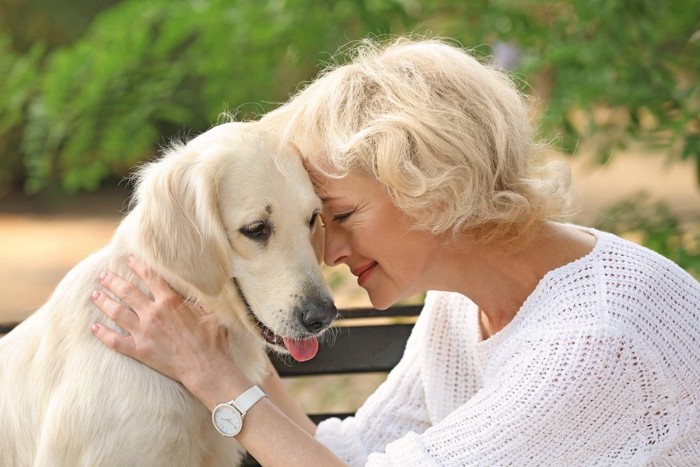 女性と顔をくっつける犬