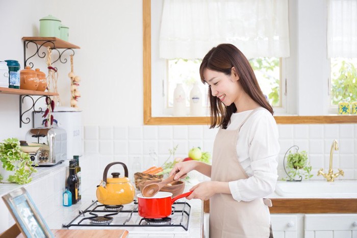 鍋を火にかける女性