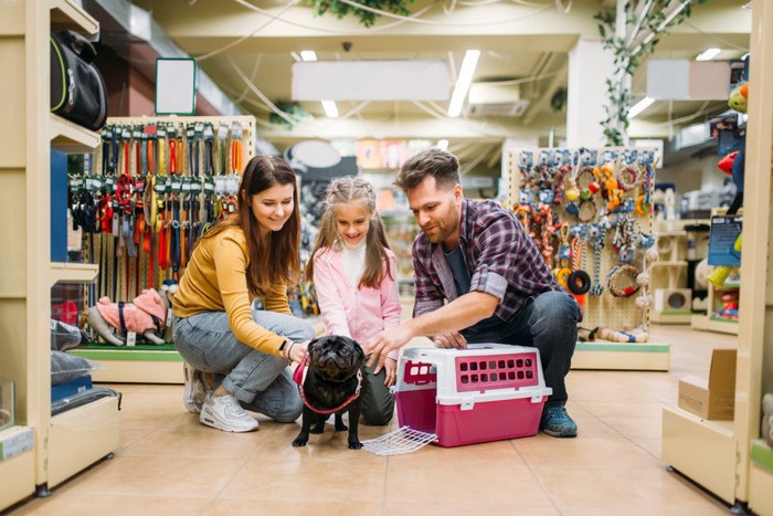 ペットショップで犬用品を選ぶ家族