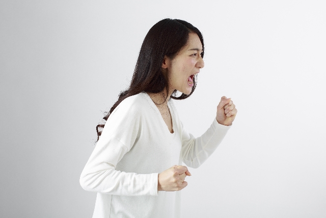 拳を振り上げて怒る女性 ロングヘア