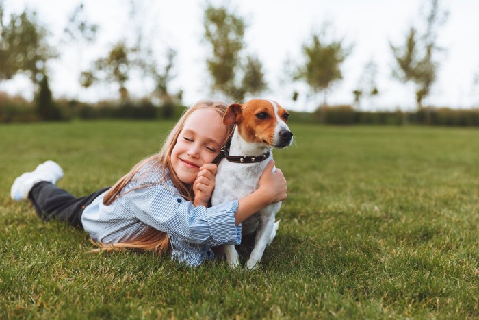 嫌そうな犬に抱き着く少女