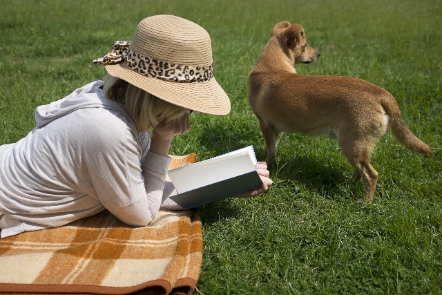 原っぱで読書する女性と犬　