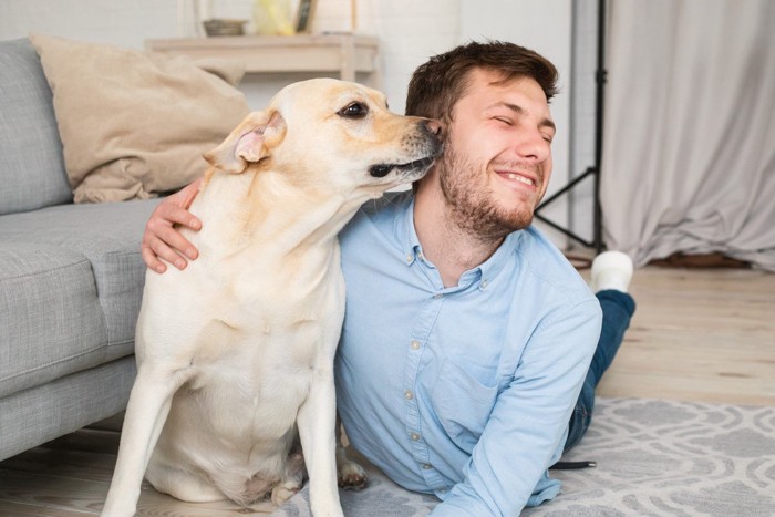 人の顔に口元を寄せる犬