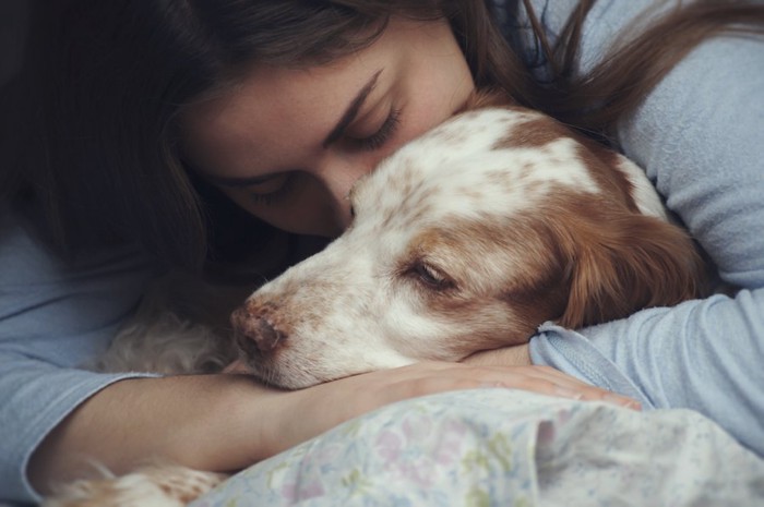 横になった犬を抱きしめる女性