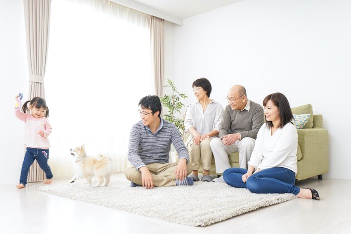 女の子と遊ぶ犬と見守る家族