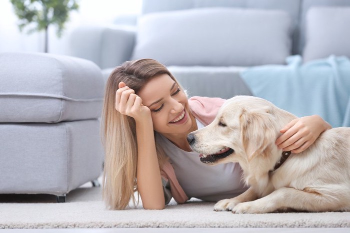 寝転がって愛犬を撫でる女性