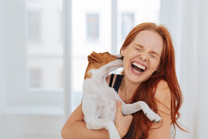 犬に耳を舐められて笑う女性