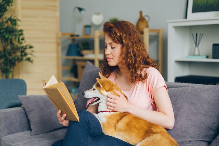 女性の膝の上に前足をのせる犬