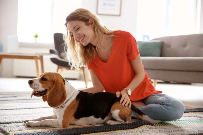 女性の隣でリラックスする犬