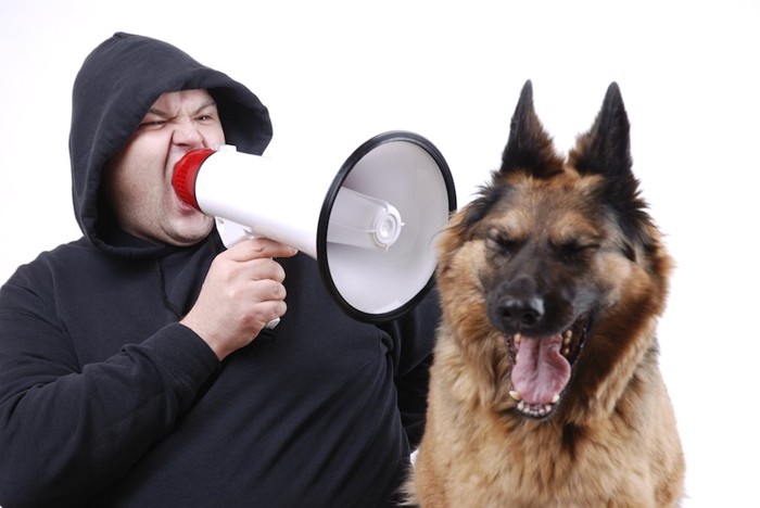 拡声器で怒鳴る男性と嫌がる犬