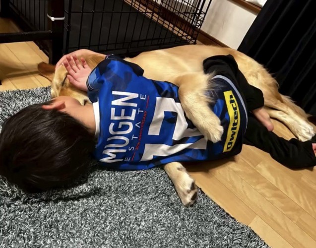 寄り添って寝転ぶ犬と人