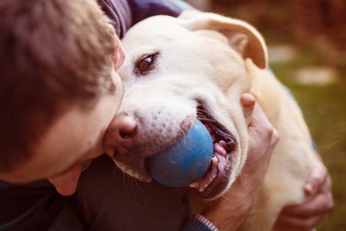 ボールをくわえた犬と男性