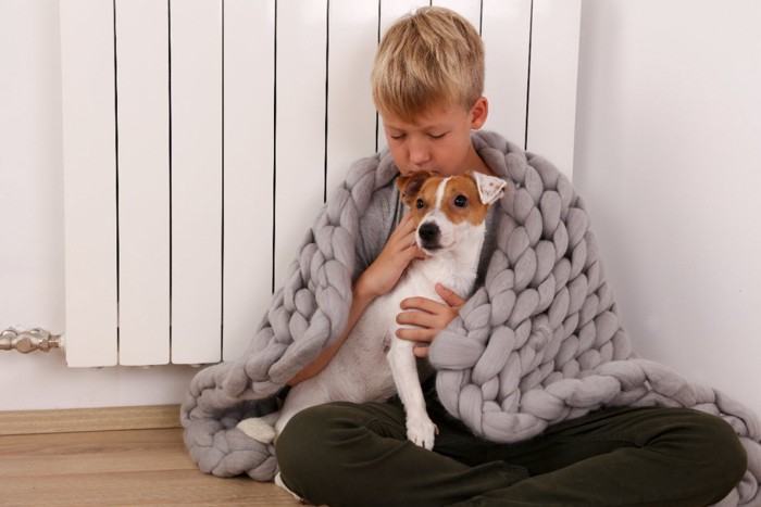 寒がる飼い主に寄り添う犬