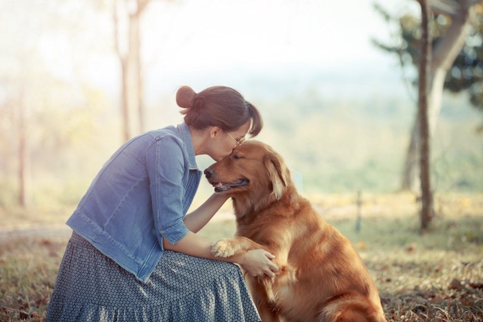 目を閉じた犬にキスをする女性