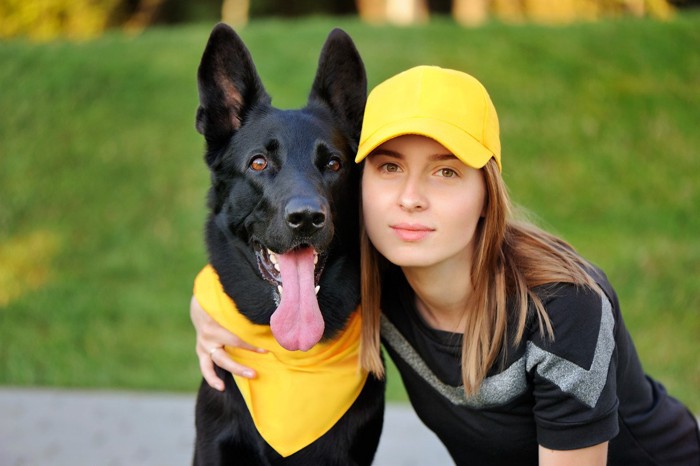 黄色いバンダナを巻いた犬と黄色い帽子の飼い主