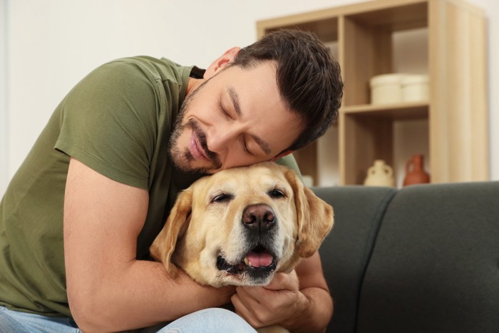 男性にハグされる犬