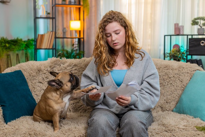 書類を見る女性と前足を置く犬