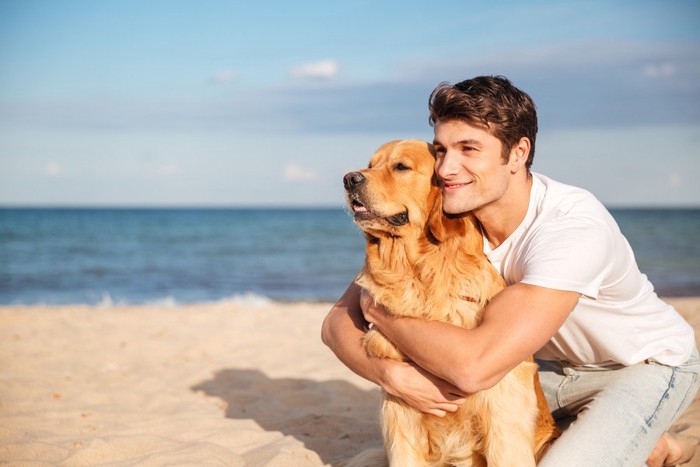 飼い犬を後ろから抱きしめる男性