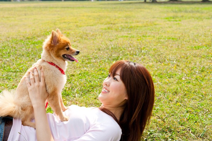 寝転ぶ女性に乗る犬