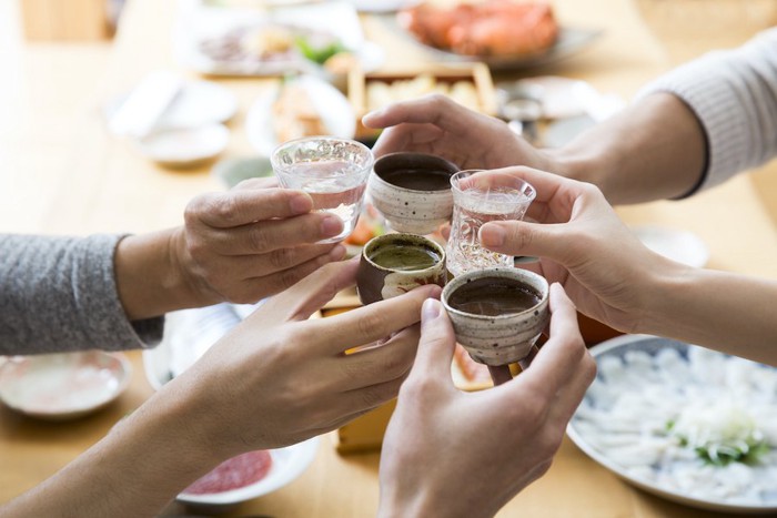 日本酒を持って乾杯する人たちの手