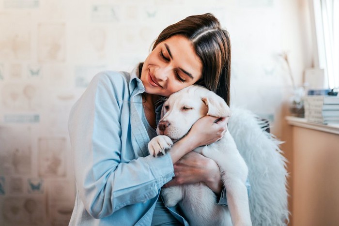 目を閉じて子犬を抱きしめている女性